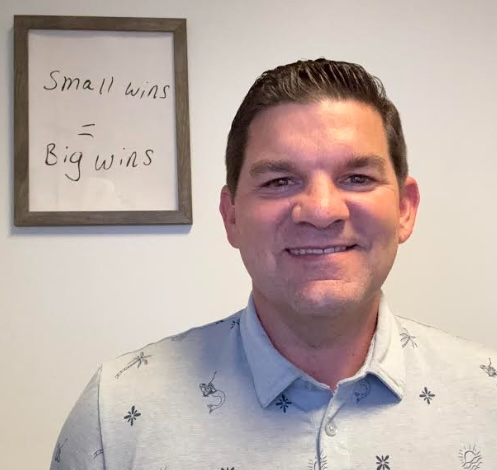 Matt Ferguson headshot with small wins big wins sign